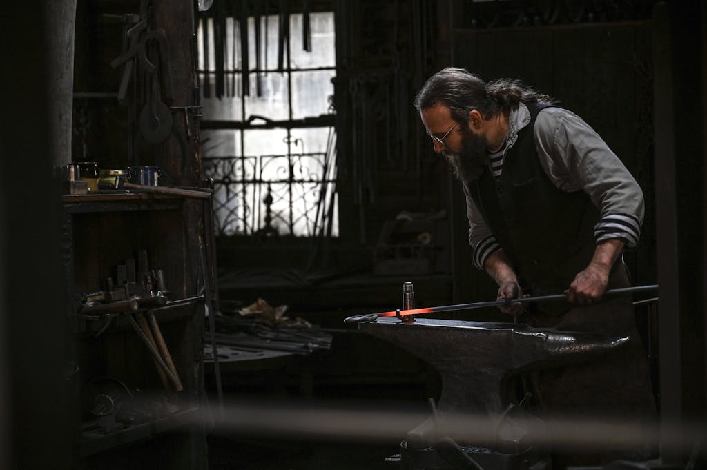 A skilled blacksmith working diligently in a dimly lit traditional forge.