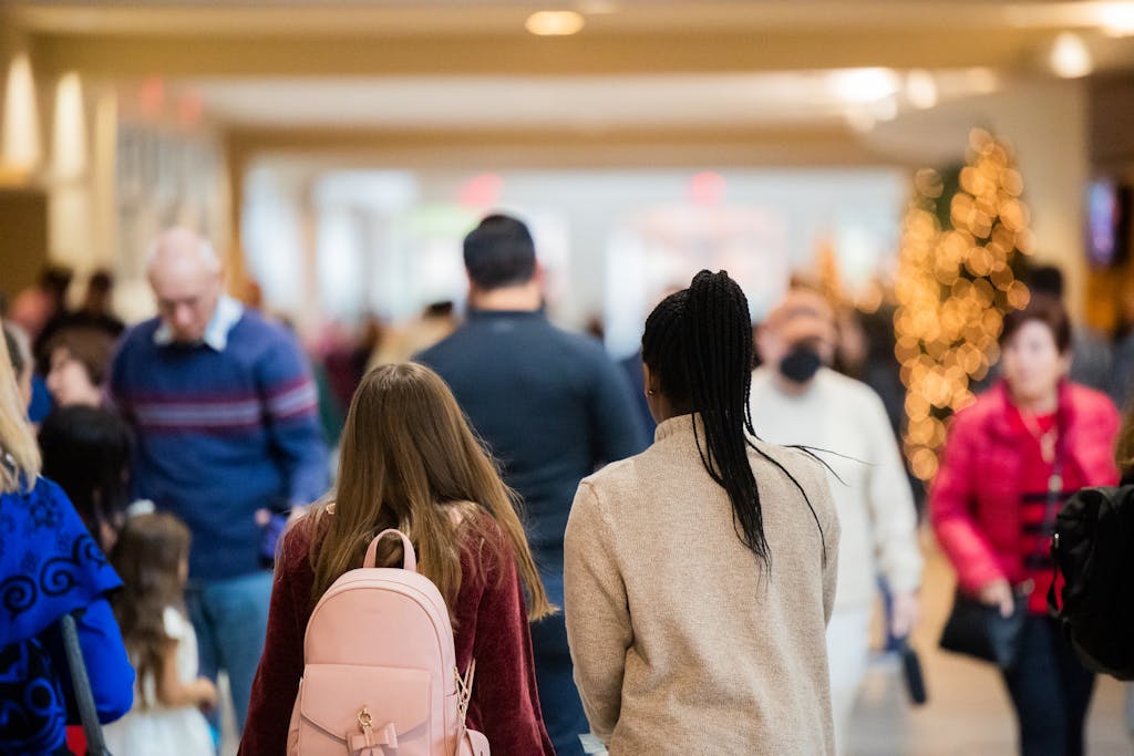 Crowded indoor mall scene with people shopping during holiday season.